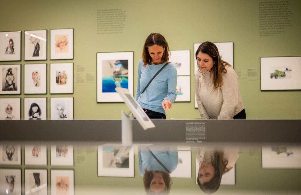 Zwei Frauen begutachten eine Ausstellung im Karikaturmuseum Krems