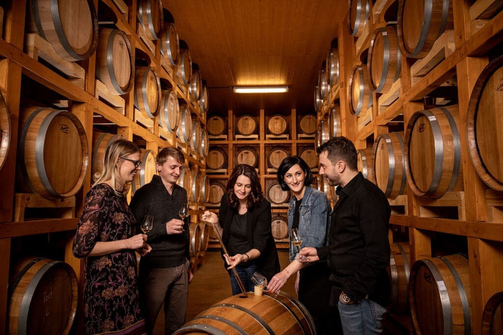 Gruppe steht in der Whisky-Erlebnis Welt bei Holzfässern und verkostet Whysky.