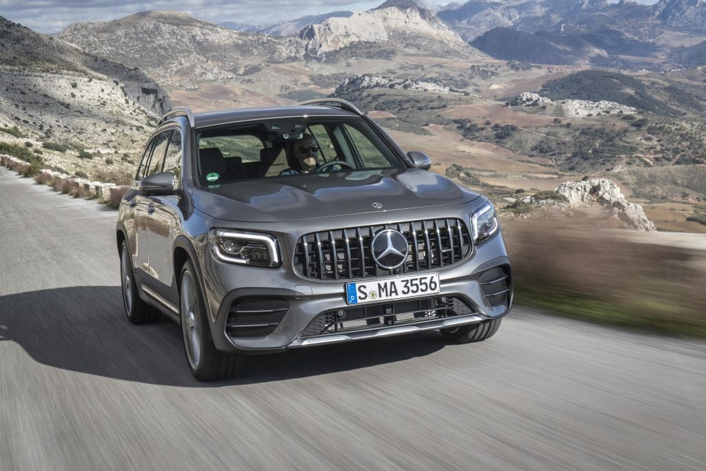 Mercedes-AMG GLB in Grau auf einer Landstraße, im Hintergrund Berge