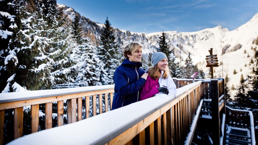 Paar steht auf der „Golden Gate Bridge der Alpen“ des Baumzipfelweges in Hinterglemm und genießt das Panorama