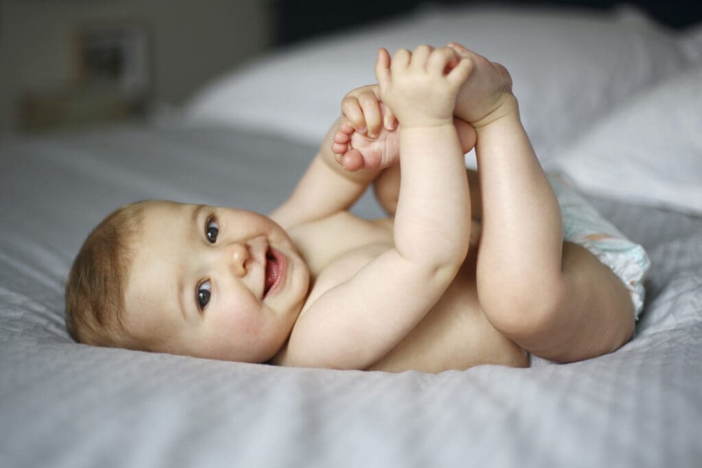 Baby liegt auf dem Rücken im Bett