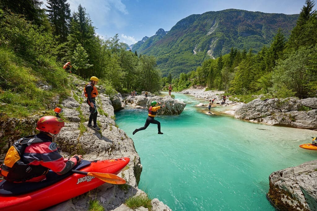 Ein Mann springt von einem Felsen in den Fluss Soča