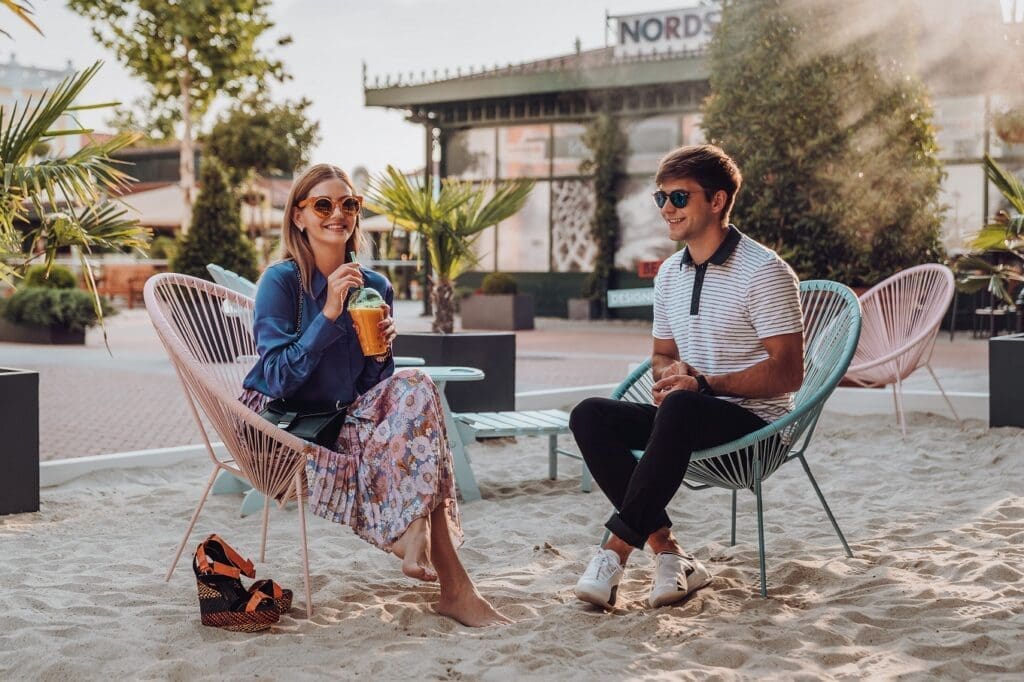 Junge Frau und junger Mann sitzen entspannt am Beach im Designer Outlet Parndorf