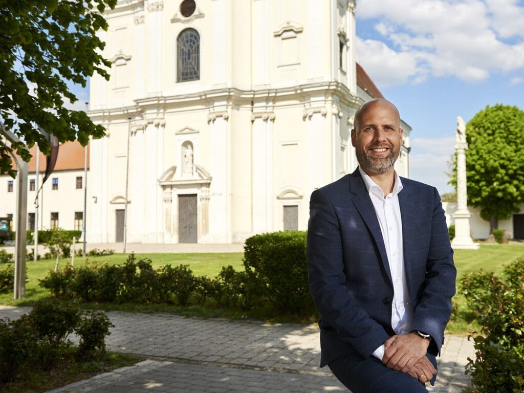 Hannes Schmid vor der Basilika in Frauenkirchen an einem sonnigen Tag.