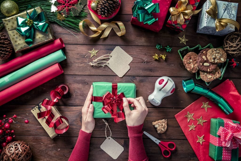 Weihnachtsgeschenke am Tisch platziert mit Scheren, Geschenksbändern und Schleifen.