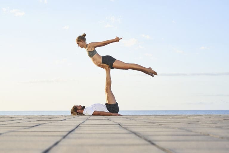 Pärchen beim Acro-Yoga vor weitem blauen Horizont.