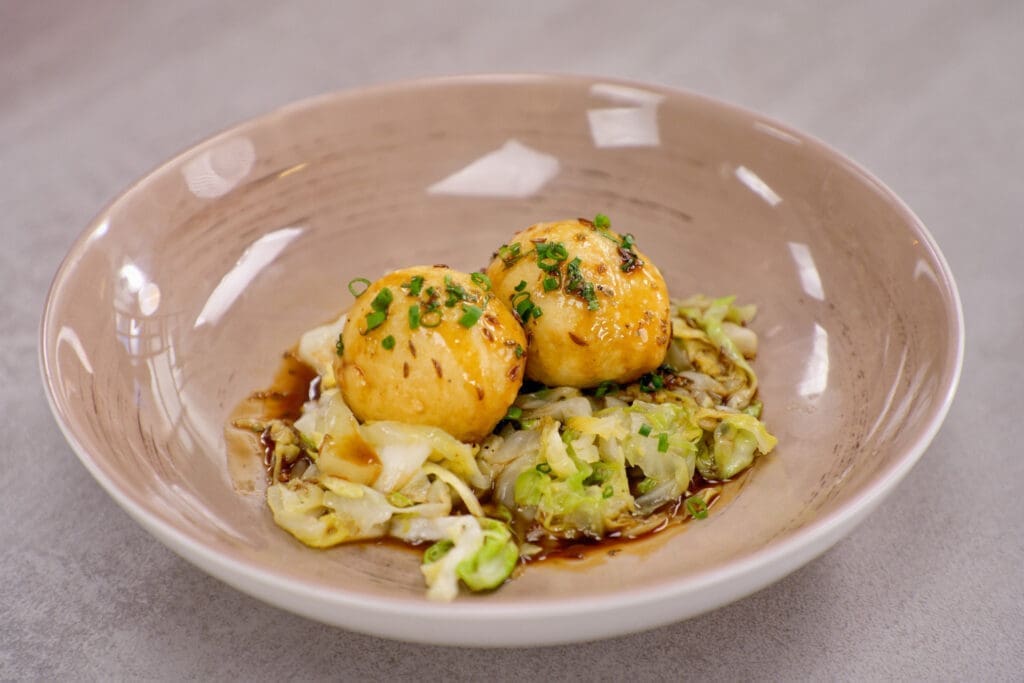 Zwei Grammelknödel auf Spitzkraut in einem tiefen teller