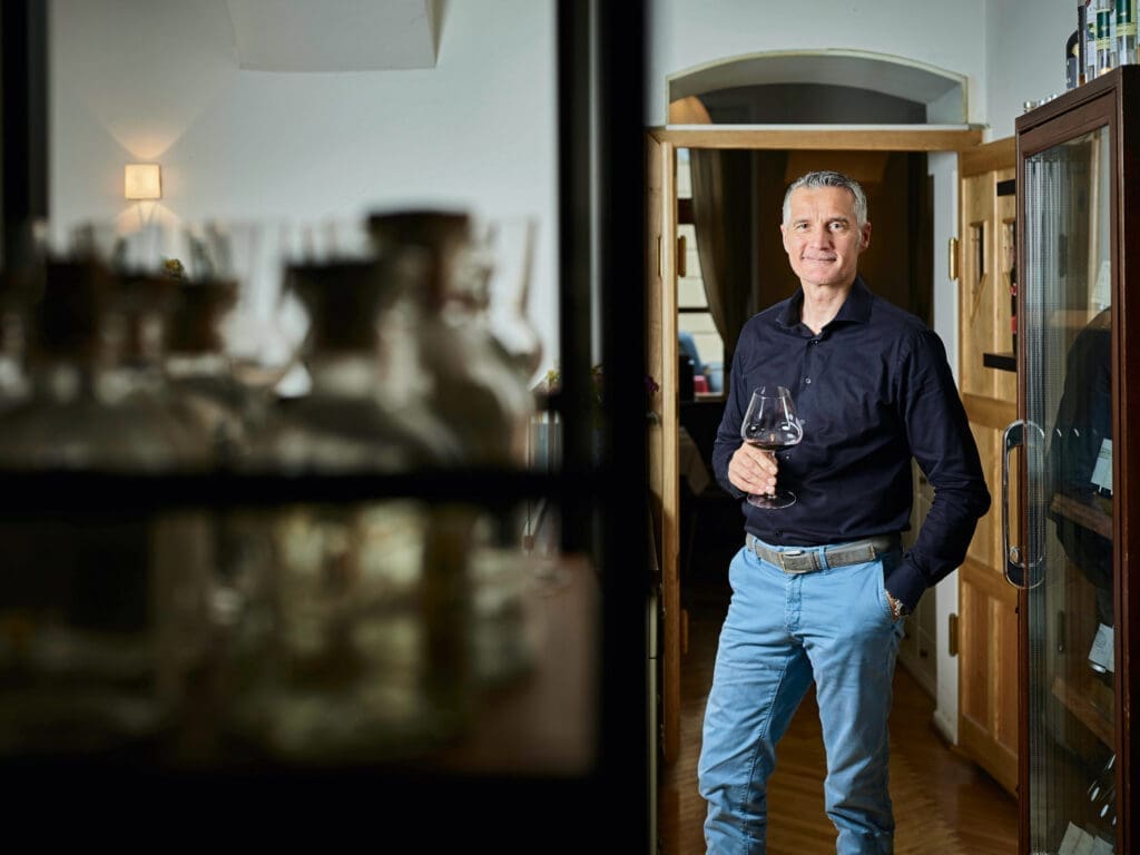 Hermann Botolen mit einem Glas Wein in der Hand im Weinkeller