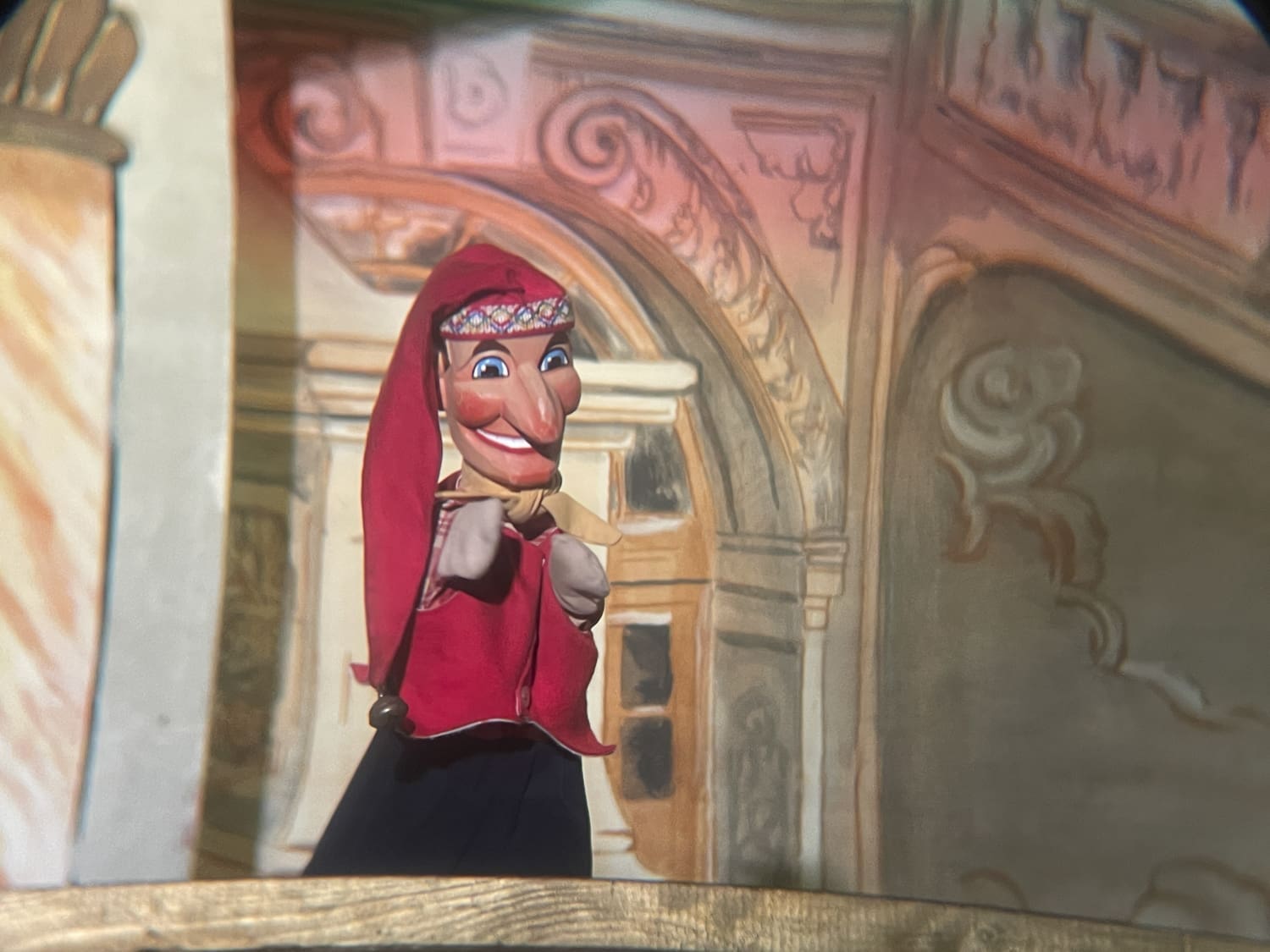 Kasperl mit roter Zipfelmütze grinst das Publikum an.