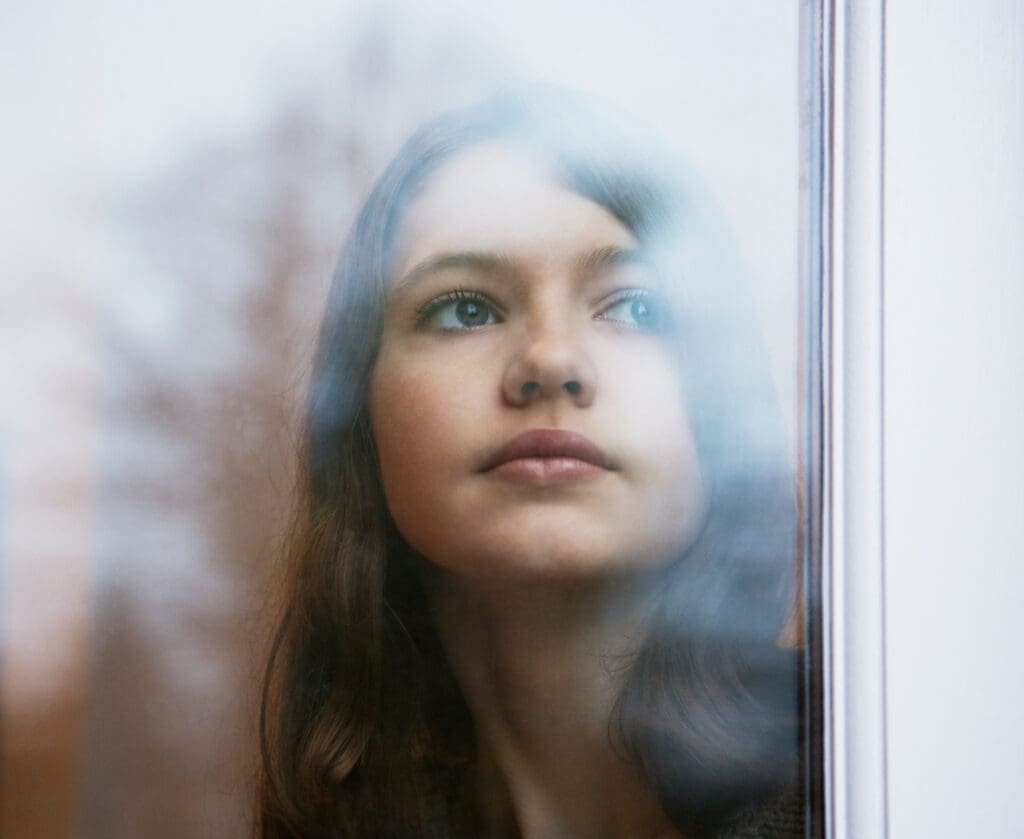 Jugendliche schaut traurig aus dem Fenster