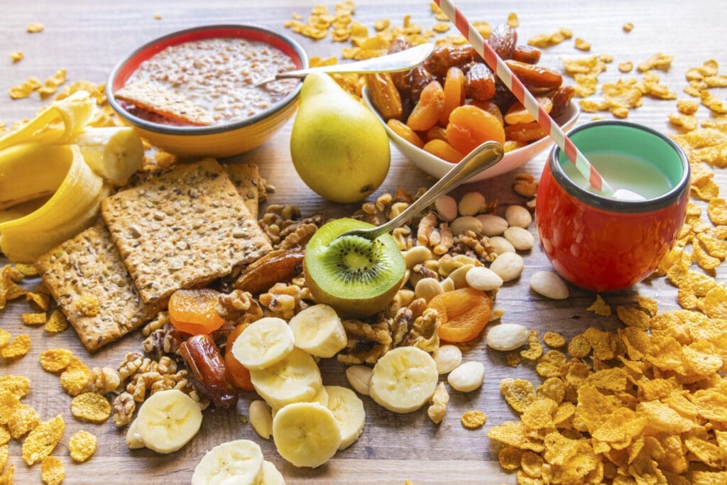 Frühstückstisch mit klassischen Kohlenhydraten wie Cornaflakes, Bananen und Brot