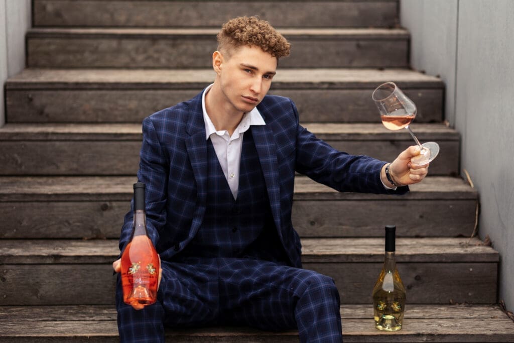 Leo Hillinger Junior mit einer Flasche Wein und einem Weinglas in der Hand