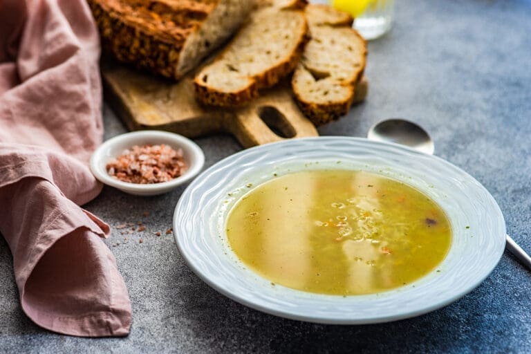 Teller mit Suppe und Brot im Hintergrund