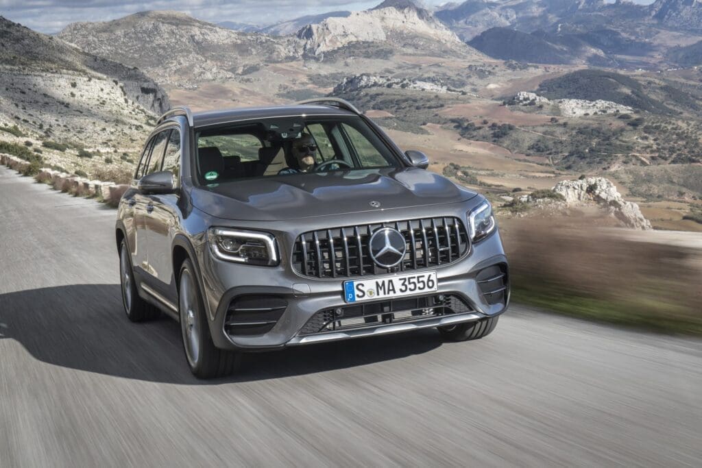 Mercedes-AMG GLB in Grau auf einer Landstraße, im Hintergrund Berge