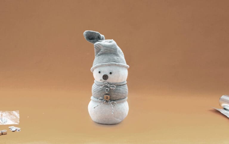 Gebastelter Schneemann vor orangem Hintergrund