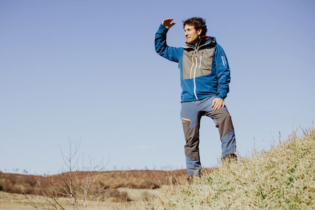 Ö3 Mikromann Tom Walek vor einer kargen Landschaft in Sportbekleidung.