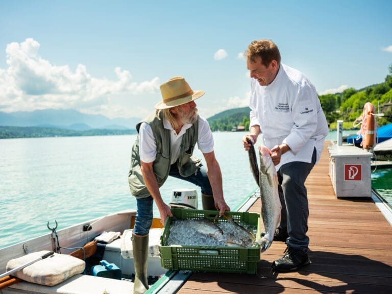 Fischer und Küchenchef stehen auf einem Badesteg am Wörthersee.