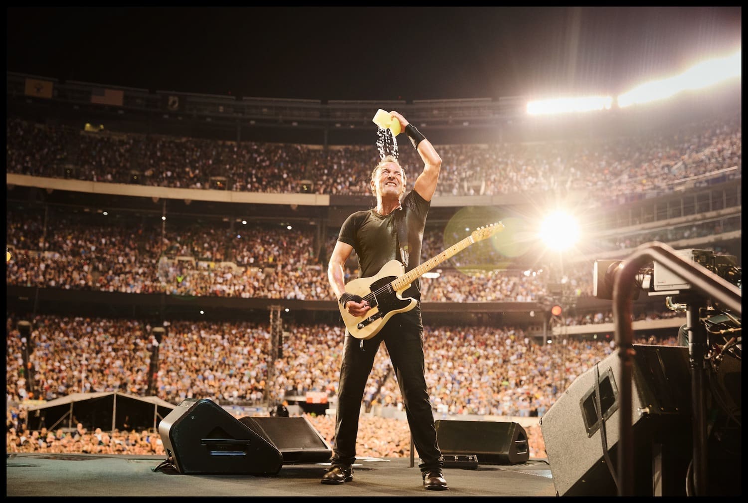 Bruce Springsteen bei einem Stadionkonzert. auf der Bühne Er drückt einen nassen Schwamm über seinem Kopf aus.