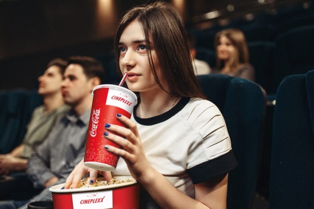 Frau im Kino trinkt Getränk aus Becher