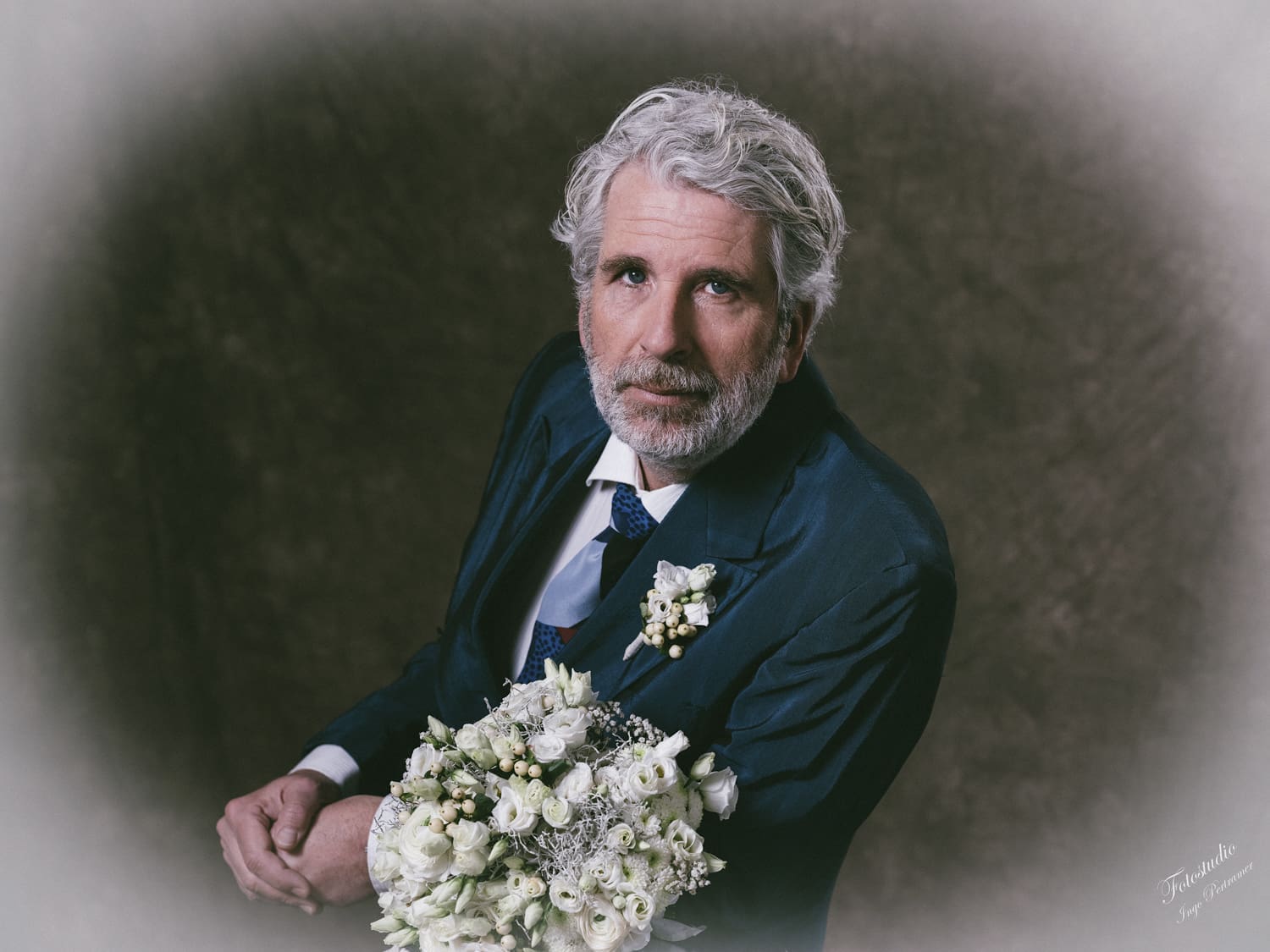 Ein Mann steht mit einem Brautstrauß vor einer Fotoleinwand.