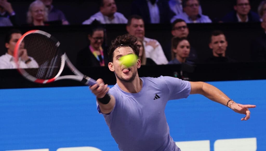 Dominic Thiem mit Schläger in der Hand und Ball vor dem Gesicht sowie ausgestreckter Zunge.