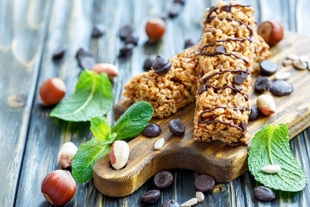 Granola Bars auf einem Schneidebrett mit Minze, Haselnüssen und Schokodrops.