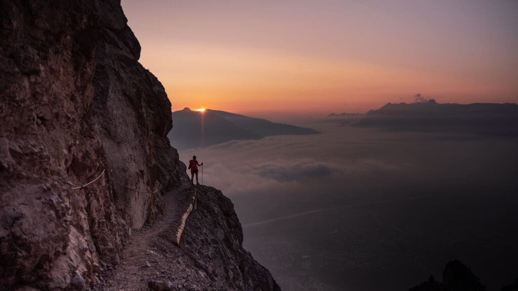 Frau beim Wandern in Liechtenstein blickt auf Sonnenaufgang bei Nebel