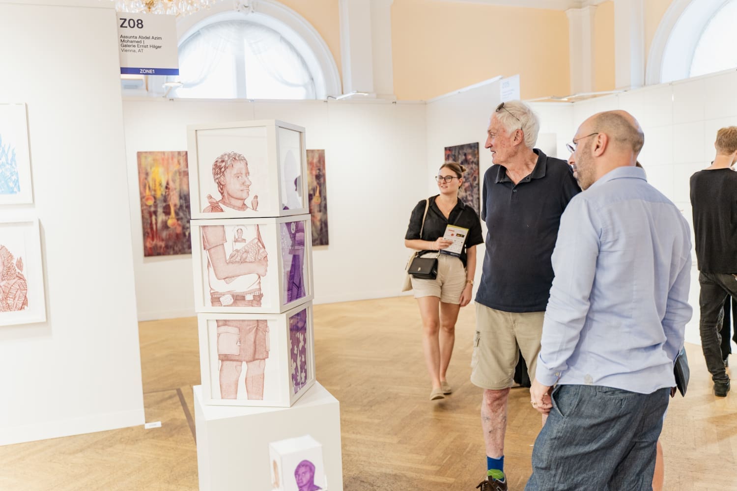 Personen betrachten moderne Kunstwerke in einem Wiener Altbau