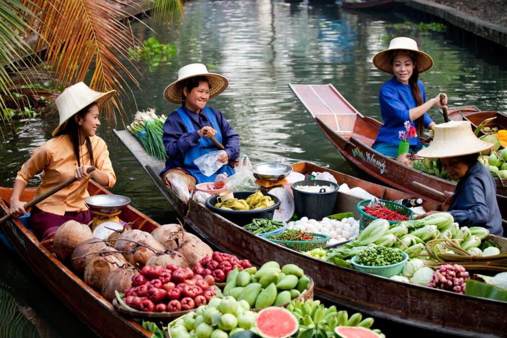 Drei Frauen in kleinen Booten beim Floating Market am Wasser