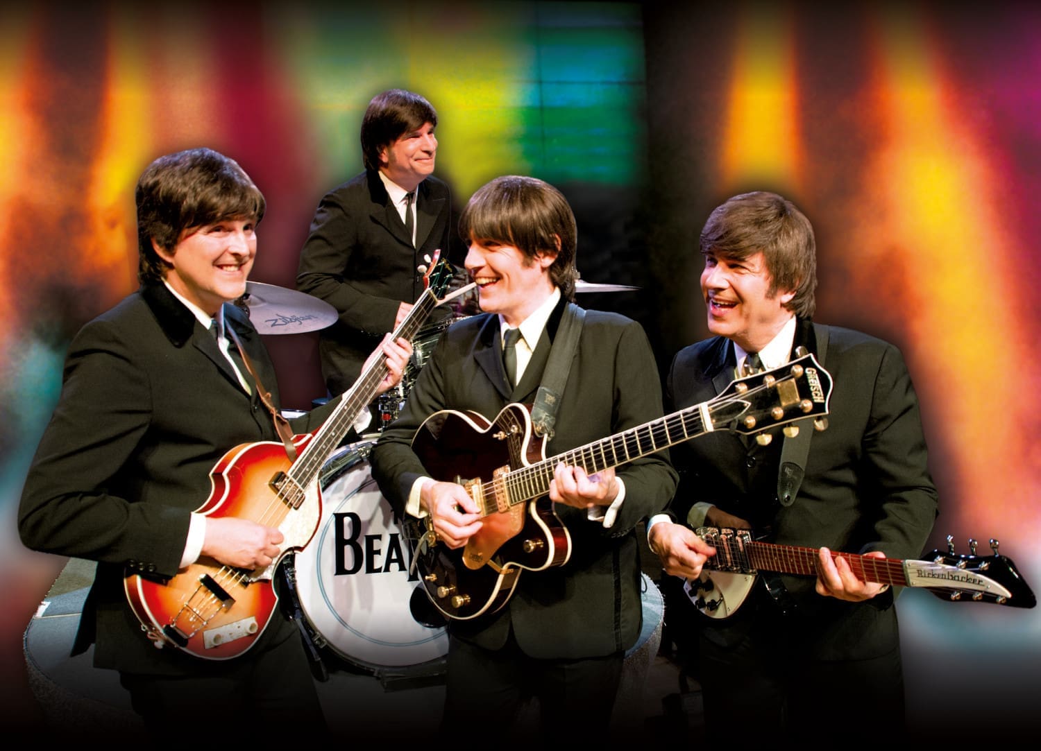 4 Musiker, die vor buntem Hintergrund die frühen Beatles imitieren