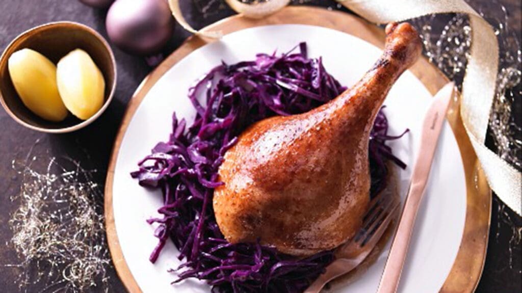 Gebratene Gänsekeule liegt auf Teller mit Rotkraut