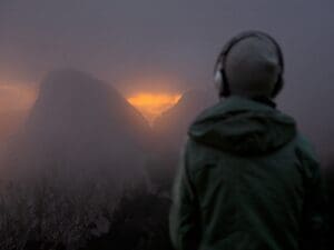 Mann mit Kopfhörern vor einer dunklen Bergkulisse