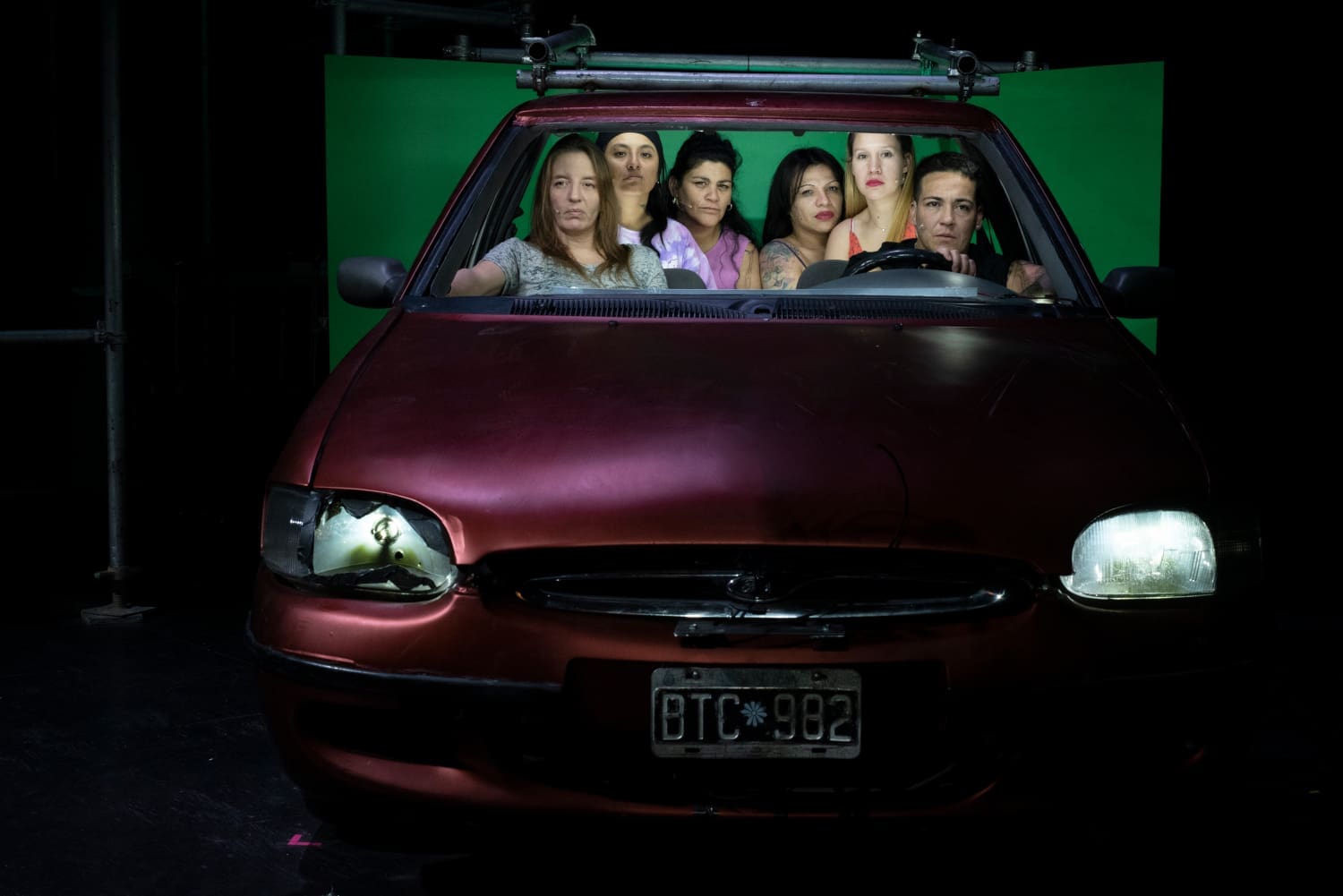 Szenefoto „The Days Out There“, sechs Frauen sitzen in einem roten Auto, Aufnahme von vorne