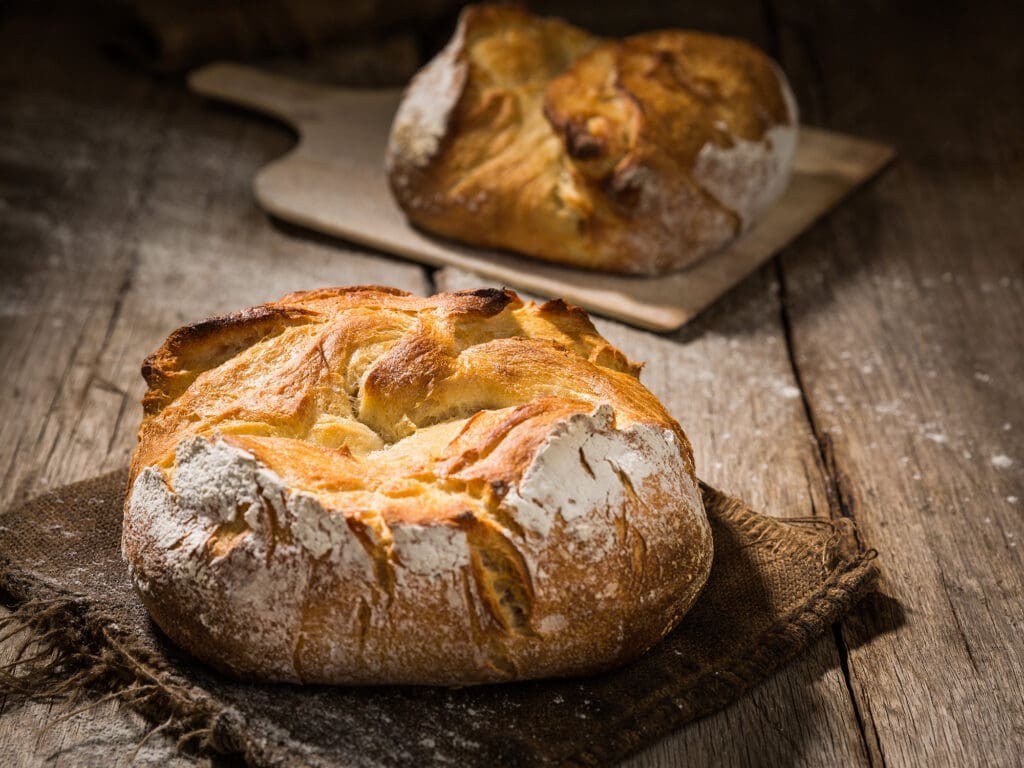 Zwei Laibe Brot auf Holzbrettern