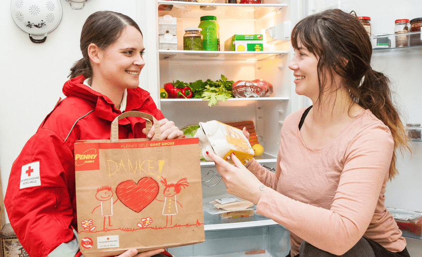 Zwei Frauen stehen vor einem Kühlschrank.