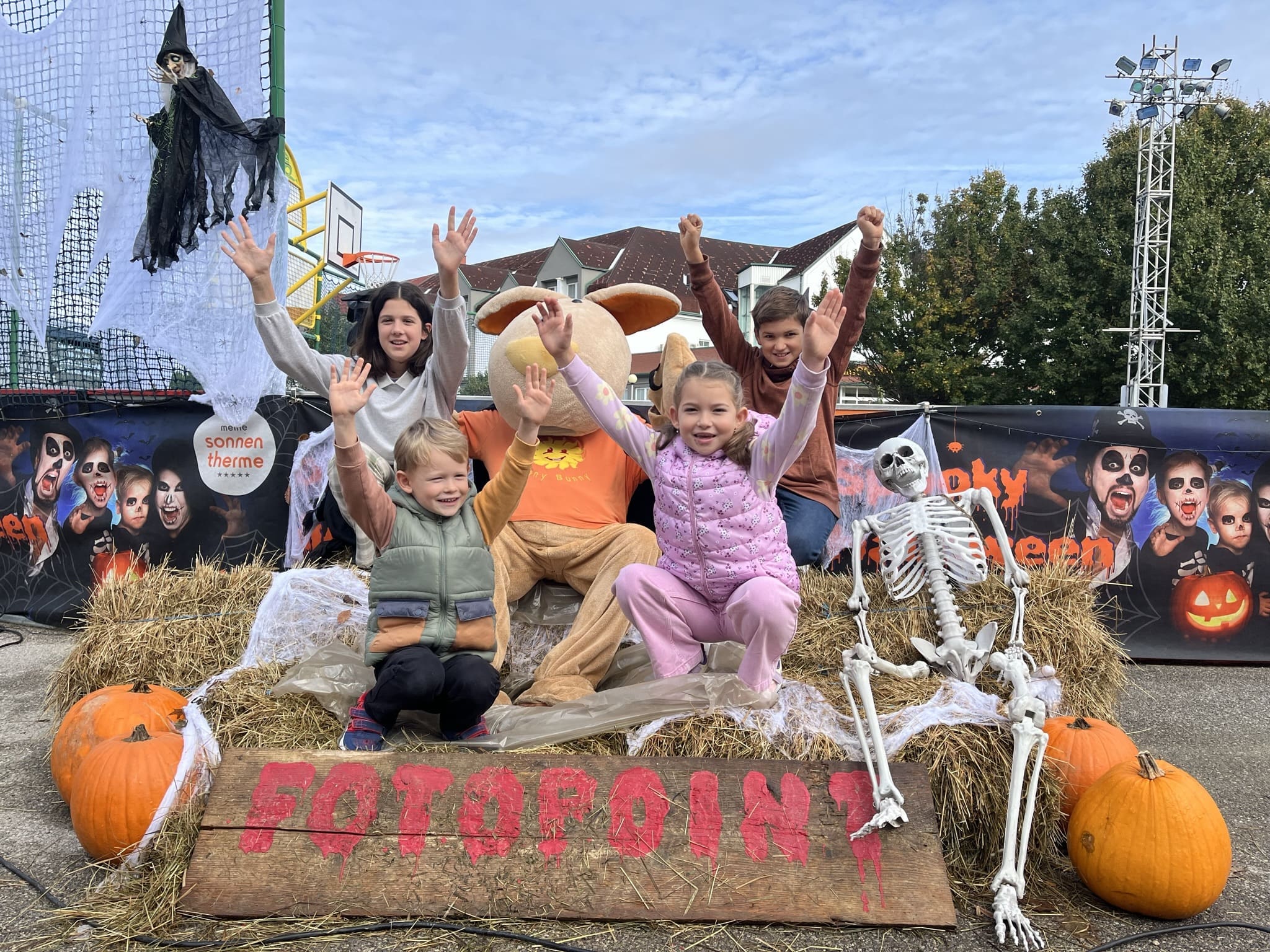 Kinder auf einem Heuballen mit Halloween-Deko