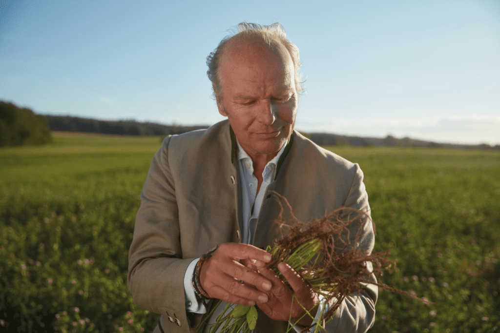 Mann steht auf einem Feld und hält Getreide in der Hand