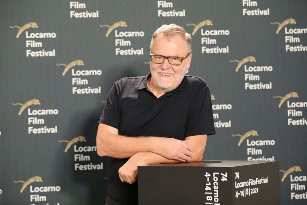 Regisseur und Drehbuchautor Stefan Ruzowitzky vor einer grauen Wand mit dem Logo des Locarno Film Festivals