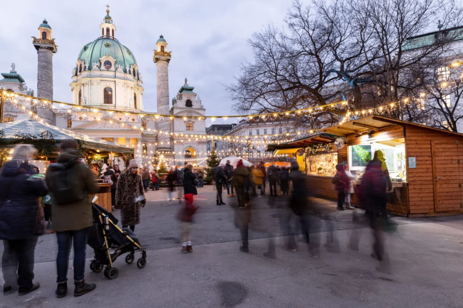 Weihnachtsmarktstände am Karlsplatz, festliche Dekoration, Lichterketten, im Hintergrund die Karlskirche