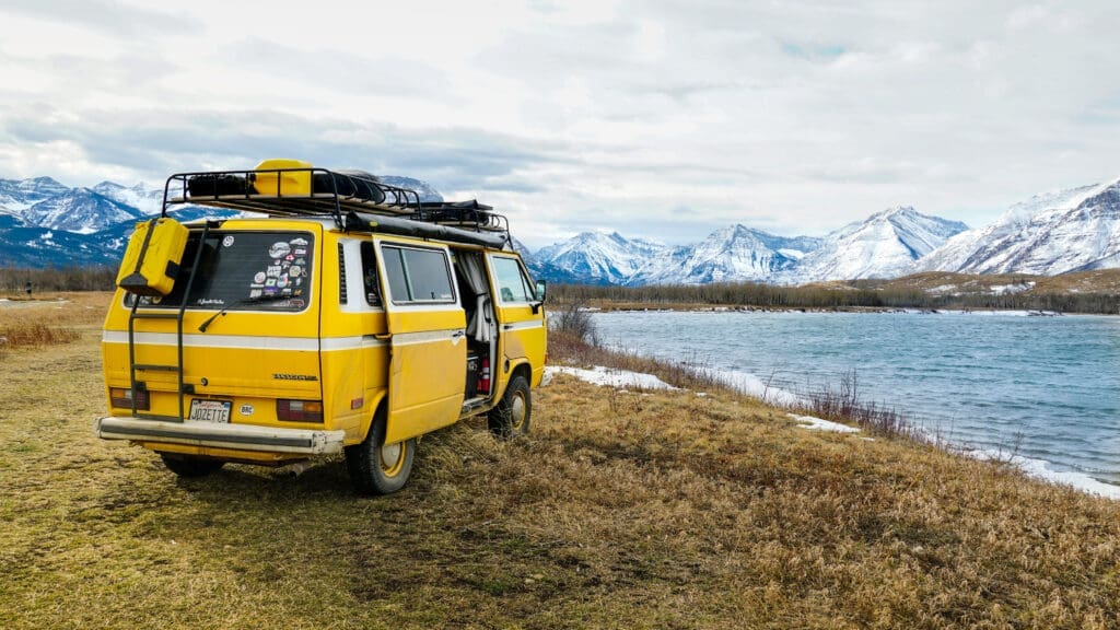 gelbes campingmobil vor beeindruckender aussicht auf see und berge