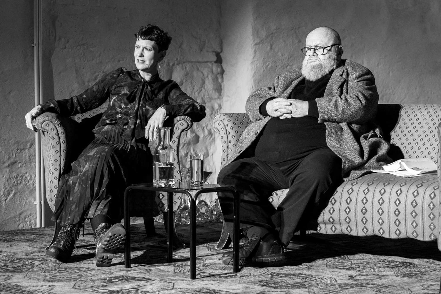 SW-Bild: Mann und Frau sitzen jeweils auf einem Sessel auf einer Bühne