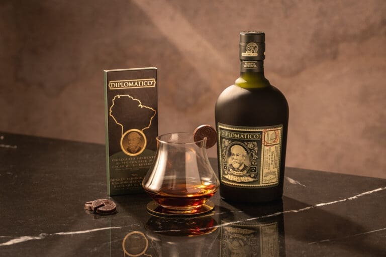 Flasche Diplomatico Reserva mit einem Glas vor braunem Hintergrund