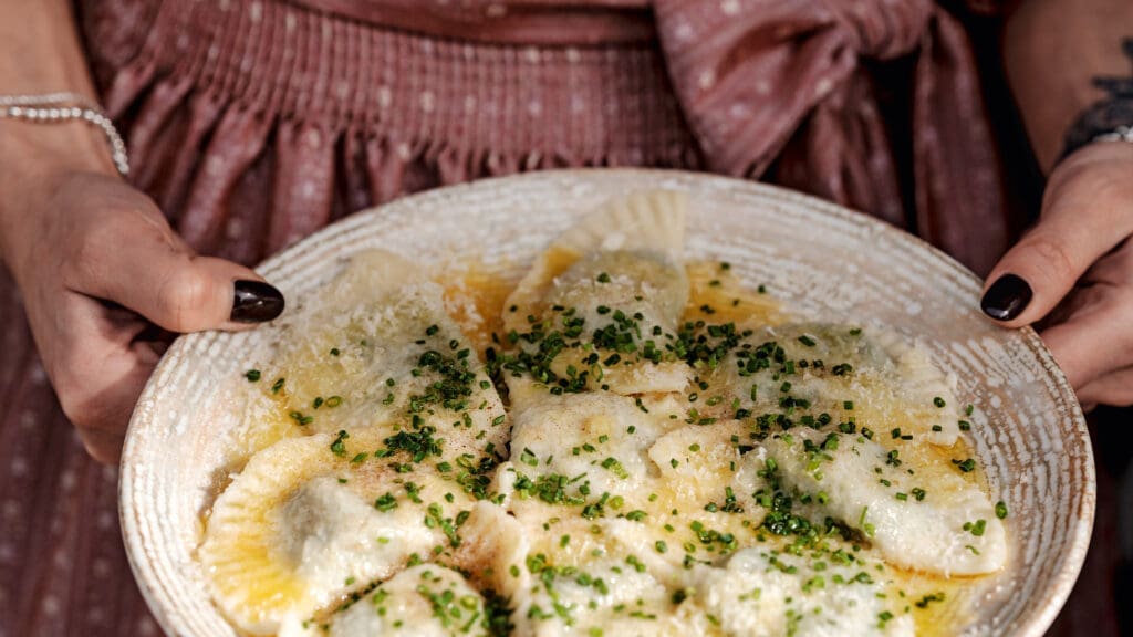 Frau hält Teller mit Schlutzkrapfen