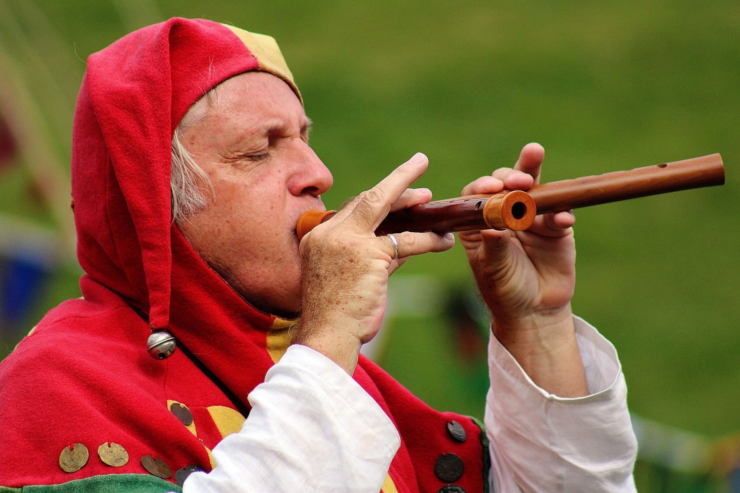 Mann in Gauklerkostüm spielt eine Doppelflöte