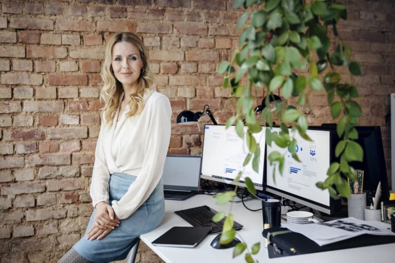 Resilienz: Frau im Büro an Schreibtisch gelehnt