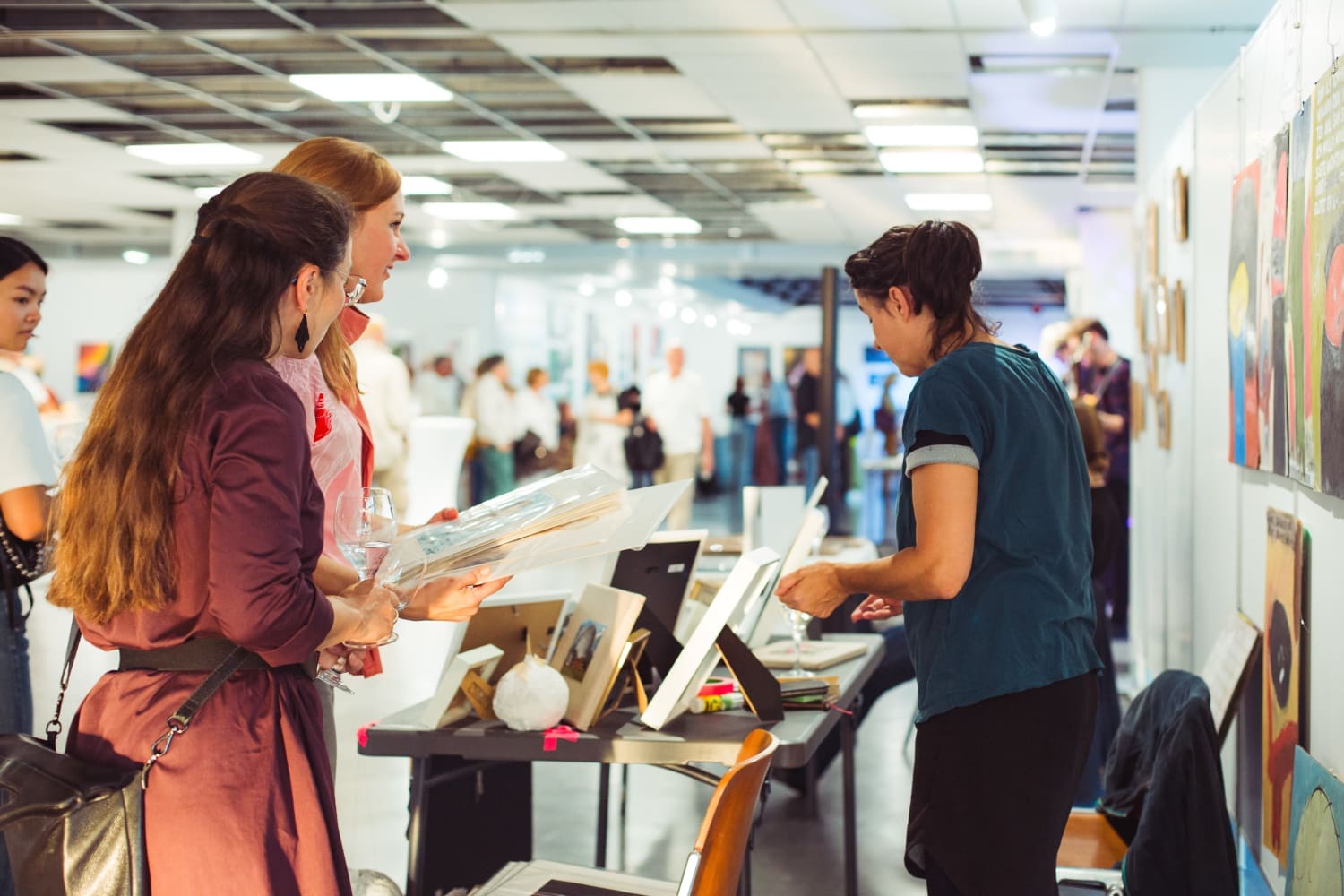 Personen stehen um einen Verkaufstisch bei einer Kunstmesse