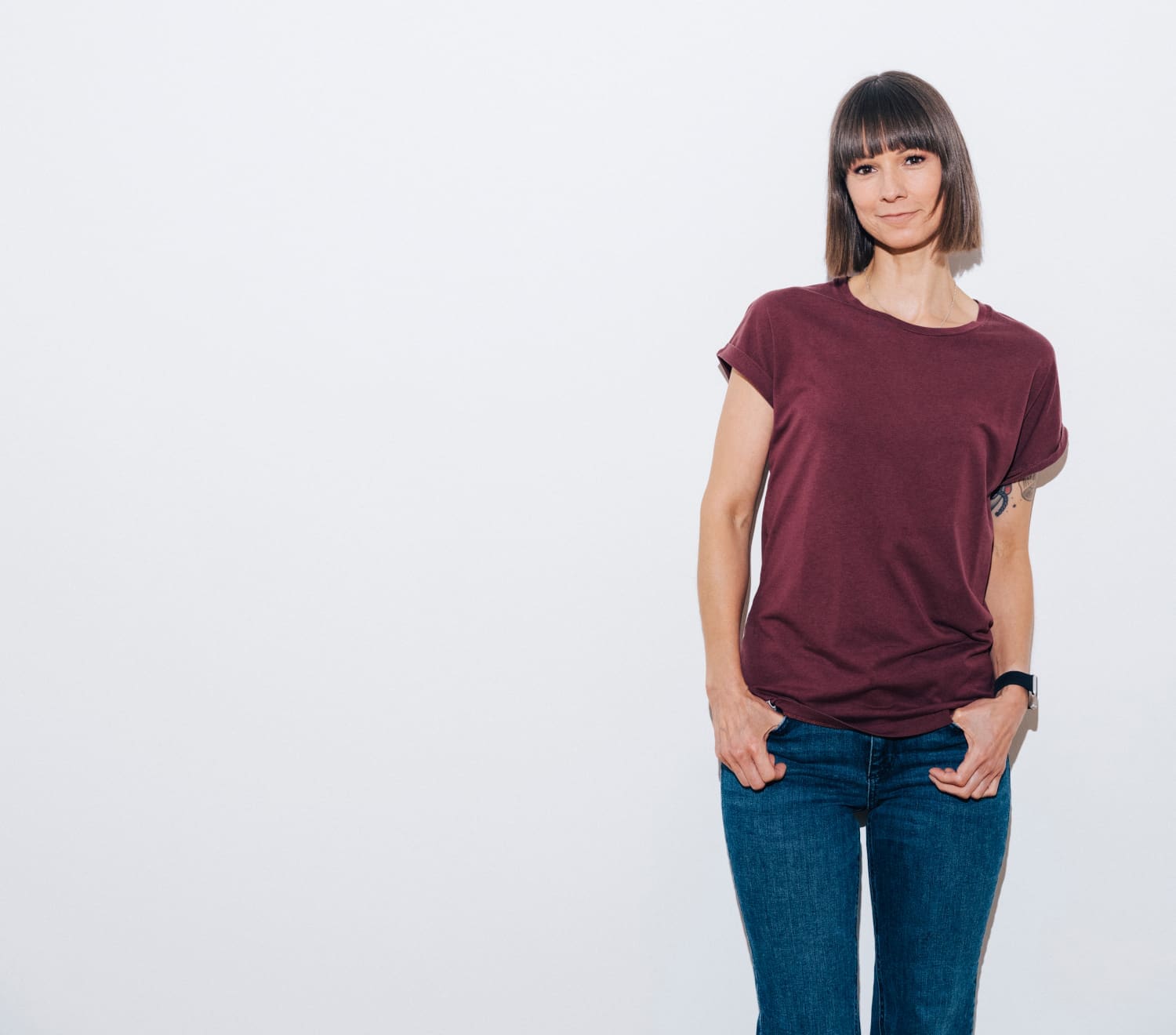 Christina Stürmer in rotem Shirt und Jeans vor grauem Hintergrund
