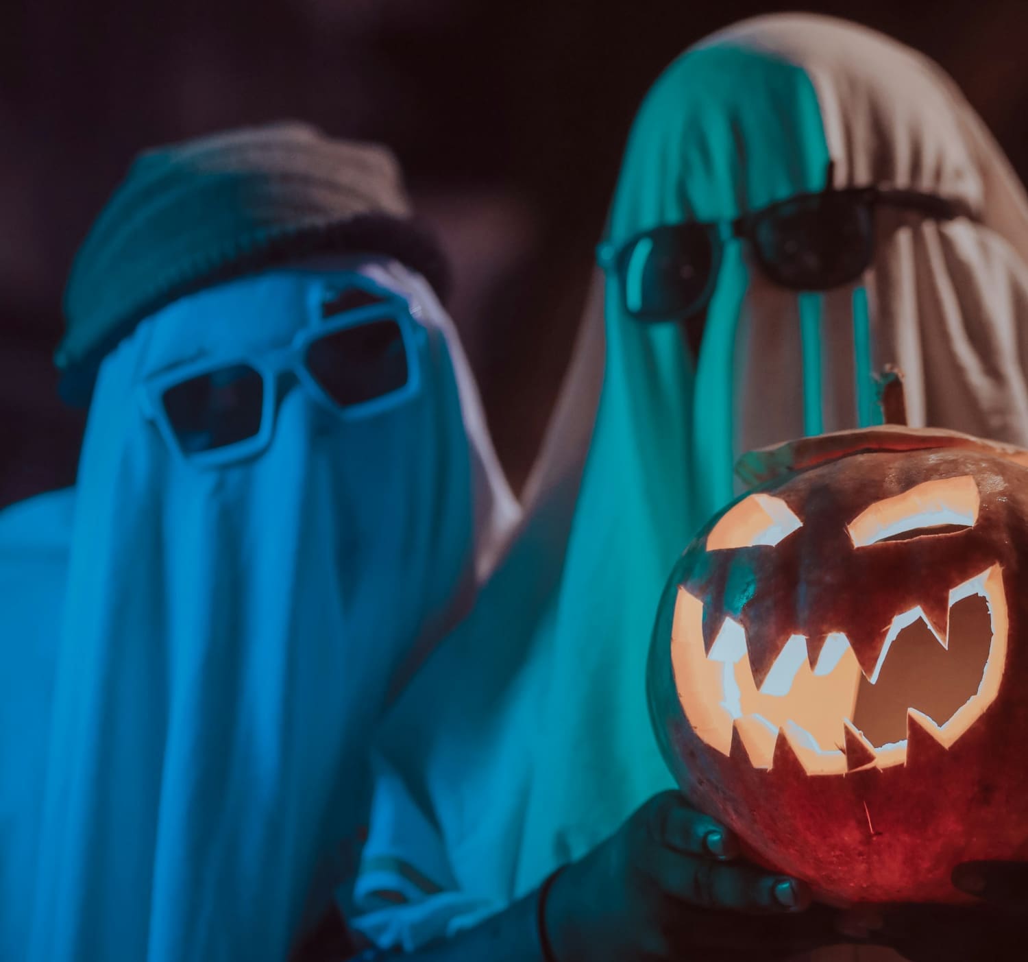 Zwei Personen in Gespensterkostüm mit Kürbis in der Hand