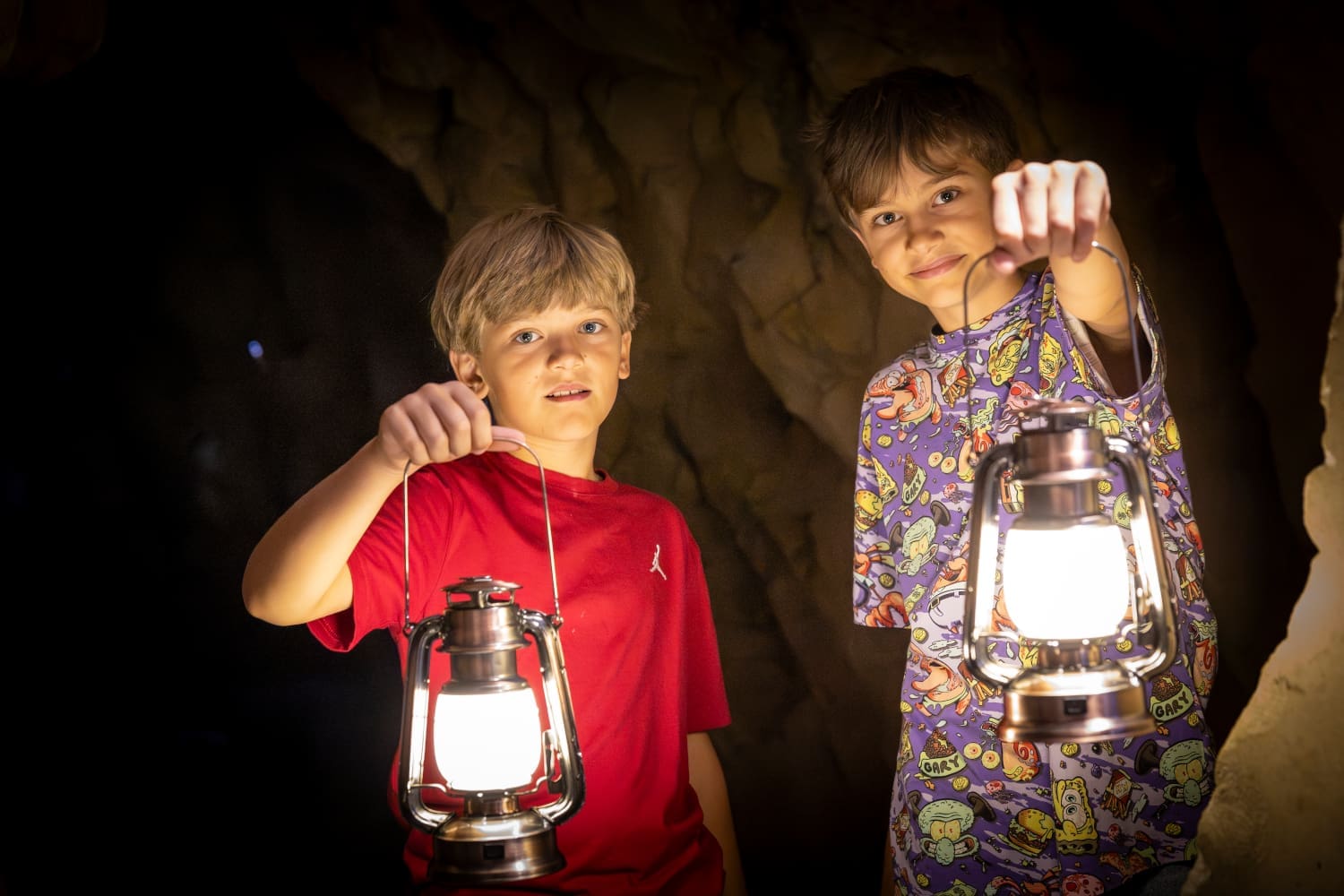 Zwei Buben mit leuchtenden Tragelampen im Dunklen