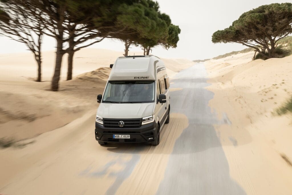 VW Grand California Dune in der Wüste vor Bäumen